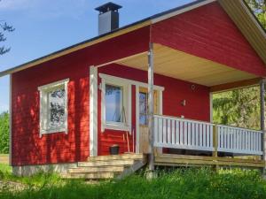 a red house with a white porch and a door at Holiday Home Villa unari by Interhome in Unari