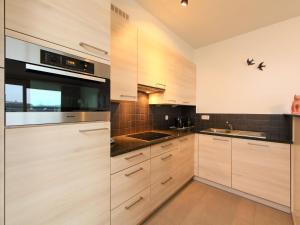 cocina con armarios de madera y horno con fogones en Apartment Residentie Greens by Interhome, en Mispelburg