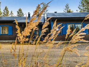 eine Blockhütte mit blauen Fenstern und hohen Grasflächen in der Unterkunft Holiday Home Salakolo 1 by Interhome in Ruka
