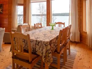 ein Esszimmer mit Tisch und Stühlen mit Blick auf das Wasser in der Unterkunft Holiday Home Pesäkolo by Interhome in Kiviperä