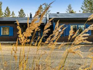 a log cabin with blue windows and tall grass at Holiday Home Salakolo 2 by Interhome in Ruka