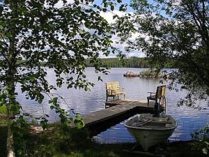 un muelle con 2 sillas y un barco en un lago en Holiday Home Ellilä by Interhome en Palonurmi
