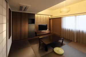 a living room with a table and a television at Hotel Gate In Kagoshima Tenmonkan in Kagoshima