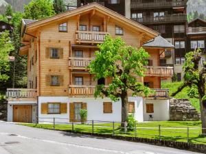 a wooden house with a balcony on the side of a street at Apartment Alpina by Interhome in Wengen