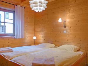 ein Schlafzimmer mit einem Bett in einer Holzwand in der Unterkunft Apartment Alpina by Interhome in Wengen