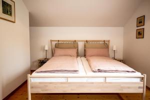 a bedroom with a white bed with two pillows at Ferienwohnungen Am Strandbad in Chieming