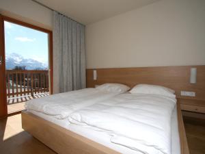 a bedroom with a large white bed and a balcony at Apartment Haus Sonne by Interhome in Erlberg