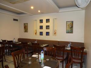 Florence Inn في نيودلهي: غرفة طعام مع طاولات وكراسي وصور على الحائط