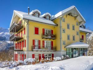a yellow building with red shutters in the snow at Apartment Mittaghorn-3 by Interhome in Wengen