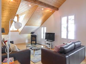 a living room with a leather couch and a tv at Apartment Mittaghorn Apt-8 by Interhome in Wengen