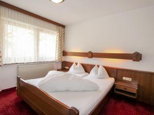 Schlafzimmer mit einem Bett mit weißer Bettwäsche und Kissen in der Unterkunft Apartment Christian-4 by Interhome in Maurach