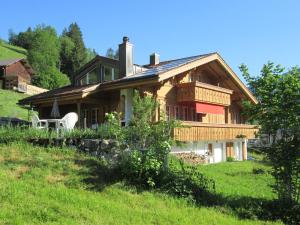 una casa de madera en una colina con un campo verde en Apartment Isabelle by Interhome, en Lenk