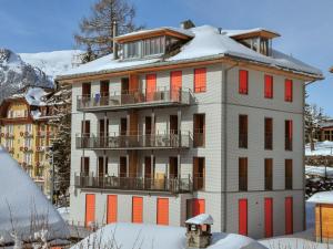 a building with red windows and a snow covered roof at Apartment Eden by Interhome in Wengen