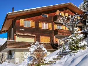 a large wooden house with snow on the ground at Apartment Sulegg by Interhome in Wengen