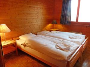 オヴロナにあるChalet Ardévaz I by Interhomeのランプ2つ付きの木造の部屋の大型ベッド1台