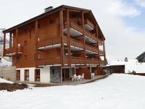 un grand bâtiment en bois avec de la neige au sol dans l'établissement Apartment Fénestral 301 by Interhome, à Ovronnaz