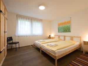 een slaapkamer met twee bedden en een stoel erin bij Apartment Bergfrieden Apt- 2 by Interhome in Wengen