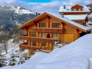 ein Blockhaus im Schnee mit einem Berg in der Unterkunft Apartment Panorama by Interhome in Wengen