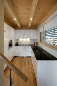 レンクにあるApartment Buggeli A by Interhomeの白いキャビネットと木製の天井が備わるキッチン