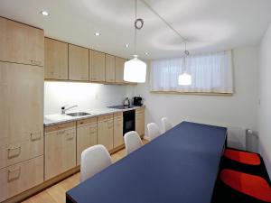 uma cozinha com uma mesa azul e cadeiras brancas em Apartment Firstli by Interhome em Lenk