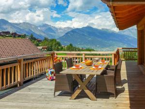 una terrazza in legno con tavolo, sedie e montagne di Chalet D'Arby by Interhome a Nendaz