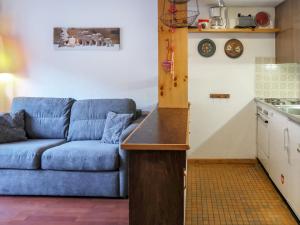a living room with a blue couch and a kitchen at Apartment Beau-Séjour 24 by Interhome in Nendaz