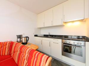 ツェルマットにあるApartment Mirador-2 by Interhomeの白いキャビネットと赤いソファ付きのキッチン
