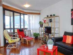 ein Wohnzimmer mit einem schwarzen Sofa und bunten Stühlen in der Unterkunft Apartment Residenza Cassarate Lago-1 in Lugano