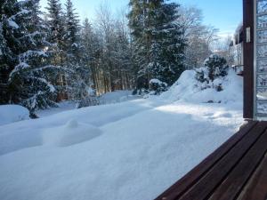 a yard covered in snow with a wooden bench at Holiday Home Zum munteren Eichhörnchen in Dittishausen