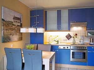 eine Küche mit blauen Schränken sowie einem Tisch und Stühlen in der Unterkunft Apartment Witthuus-Langeoog by Interhome in Norddeich