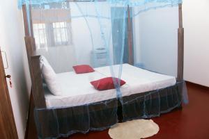 1 dormitorio con cama con dosel y almohadas rojas en Malsha Villa, en Weligama