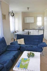 a living room with a blue couch and a kitchen at Holiday Home Domek Joanna-2 by Interhome in Łeba