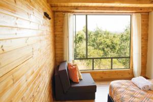 um quarto com um sofá e uma janela num chalé de madeira em Luna Llena Cabañas em Guatavita