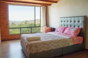 sypialnia z łóżkiem i dużym oknem w obiekcie Luna Llena Cabañas w mieście Guatavita