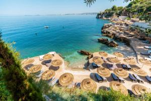 Una playa con sillas y sombrillas y el océano. en Nikaj Premium Apart-Hotel, en Vlorë
