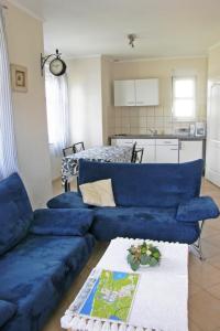 a living room with a blue couch and a kitchen at Holiday Home Domek Joanna-3 by Interhome in Łeba