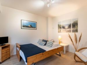 a bedroom with a bed and a tv and a chair at Apartment La Sauvagère-1 by Interhome in Carnac-Plage