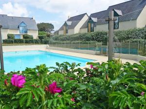 a swimming pool in front of some houses with pink flowers at Apartment Les Villas de Kermaria by Interhome in Kervoz