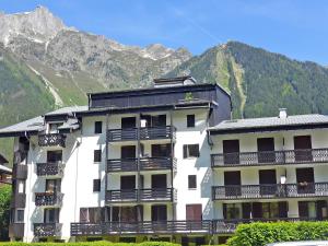 a white building with balconies and mountains in the background at Apartment Le Triolet-5 by Interhome in Chamonix