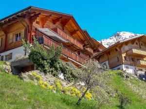 a large wooden building on a hill with a mountain at Apartment Bluemewäg Apt-R by Interhome in Wengen