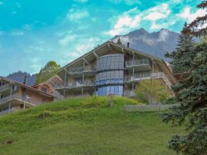 a large building on a hill with mountains in the background at Studio Silence Apt- H by Interhome in Wengen