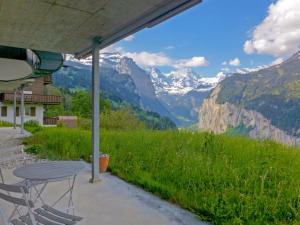 a table and chairs on a porch with a view of mountains at Studio Silence Apt- H by Interhome in Wengen