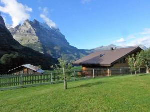 uma casa num campo com montanhas ao fundo em Apartment Lohnerhus-2 by Interhome em Grindelwald