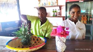 dwoje ludzi stojących przy stole z miską kwiatów w obiekcie Menai Bay Beach Bungalows w mieście Unguja Ukuu