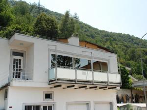 Cette maison blanche dispose d'un balcon avec une montagne en arrière-plan. dans l'établissement Apartment Casa Zappa by Interhome, à Brusino Arsizio