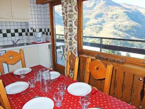 a table with plates and glasses on it with a mountain view at Apartment Oisans 37 by Interhome in Les Menuires