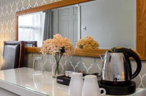 a kitchen counter with a tea kettle and flowers on it at Clifden House by Nina in Dublin
