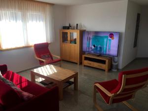 un soggiorno con TV, tavolo e sedie di Apartment Amici 1- Stock Allegra by Interhome a Riederalp