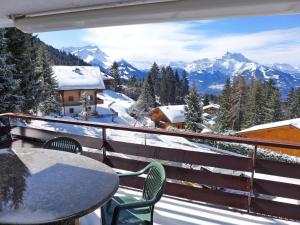 a balcony with a table and chairs and snow covered mountains at Apartment Schuss 23 by Interhome in Villars-sur-Ollon