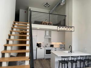 a loft apartment with a staircase and a kitchen at Main Street Farmhouse City Retreat by Hollyhock in Louisville